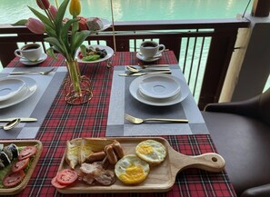 A breakfast table set with plates, cutlery, and a wooden board with eggs and sausages.