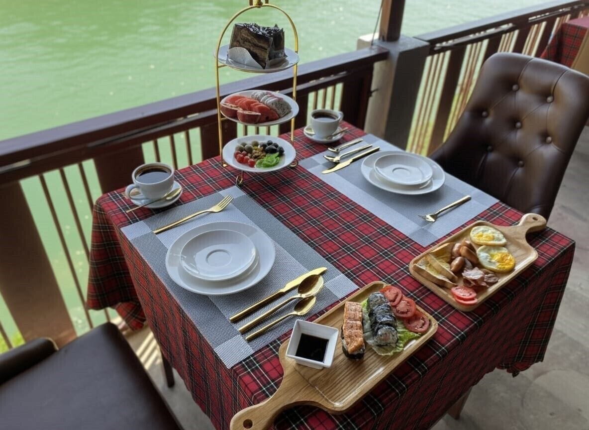 A dining table set with a red and black checkered tablecloth, plates, cutlery, and a tray with food items.