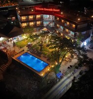 A resort with a swimming pool, outdoor seating, and a well-lit building.