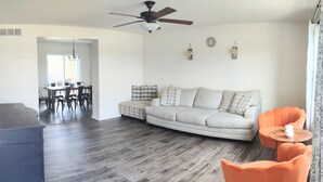 A living room with a sofa, a dining table, and chairs. There is a ceiling fan and a clock on the wall. - Sunset Family Point (Independence)