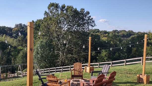 An outdoor seating area with wooden chairs and tables, surrounded by a wooden fence and trees. - Sunset Family Point (Independence)