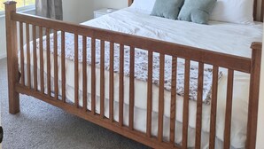 A bedroom with a wooden bed, white bedding, a window with curtains, and a ceiling light fixture. - Sunset Family Point (Independence)