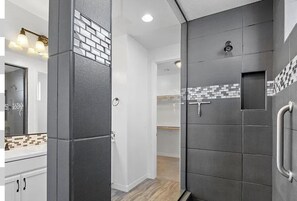A master bathroom with a large mirror, a towel rack, and a shower area. - Cozy Desert Winter Haven (Peoria)