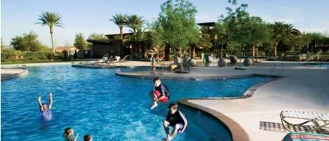 A swimming pool area with multiple lanes, palm trees, and a lounge chair.