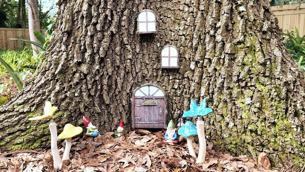 A tree with a small door labeled "Welcome" and miniature figures including a gnome and a mushroom. - Duck Pond Getaway (Gainesville)