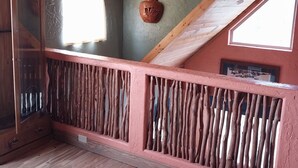 Een kamer met een schuine balken plafond, houten vloer en een rustieke houten balustrade.