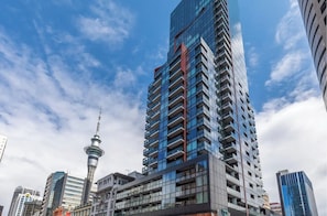 Un grattacielo con una moderna facciata in vetro, un'antenna ben visibile e vista sullo skyline urbano circostante.
