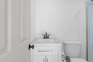 Een badkamer met een wit toilet, een wastafel met kraan en een deur.
