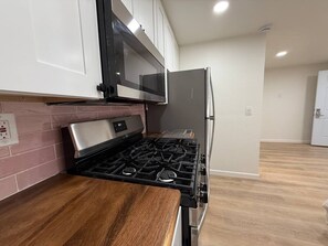 Una cocina equipada con estufa a gas, microondas y refrigerador.