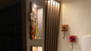 Un intérieur moderne agrémenté d’un panneau lumineux vertical, d’un miroir et d’objets décoratifs, notamment un arbre doré et des cœurs rouges.