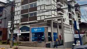 Un immeuble à plusieurs étages doté d’une architecture moderne, avec des balcons et une entrée imposante agrémentée d’une enseigne « Agibank ».
