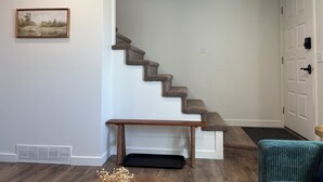 A staircase with carpeted steps, a wooden bench, a door, and a small rug at the bottom. - Coming for work?! Stay here! (Rock Springs)
