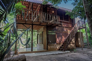Uma casa de madeira com varanda e escadaria que leva ao andar superior.