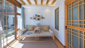 A room with a wooden bench, a wall-mounted decorative piece, and a sliding door with a grid pattern. - Lijiang Muyuntang View Hotel (Lijiang)