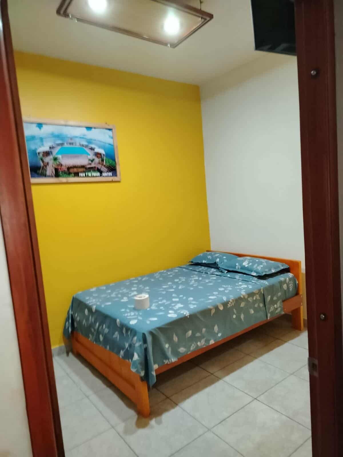 A small, single-bed room with a yellow wall and a poster of a car on the wall.