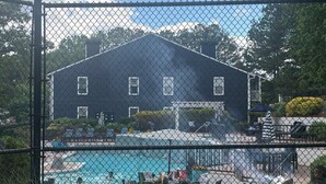 Zona de piscina con cerramiento y un edificio al fondo.