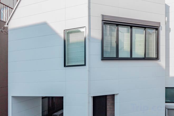 A modern building with white exterior walls, a large window with a black frame, and a smaller window above it.
