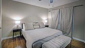 A bedroom with a bed, two bedside lamps, a ceiling fan, and a window with curtains. - Contemporary Retreat near Lakeshore (Brandon)