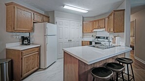A modern kitchen with wooden cabinets, a white refrigerator, a marble countertop, and a built-in sink. - Contemporary Retreat near Lakeshore (Brandon)