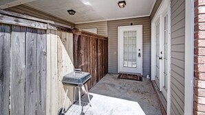 A covered porch with a grill, a door, and a brick wall. - Contemporary Retreat near Lakeshore (Brandon)
