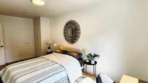 Ein Schlafzimmer mit einem Bett, Nachttischen, einem Spiegel und einer Tür.