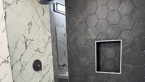 Ein Badezimmer mit Dusche, Toilette und Spiegel.