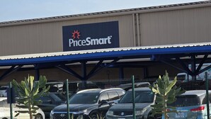 Een PriceSmart winkel met een overdekte parkeerplaats en meerdere geparkeerde auto's.