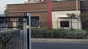 Een Wendy's restaurant met een modern design, gekenmerkt door een opvallend rood-bruin kleurenschema en een hekwerkentree.