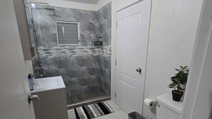 Een badkamer met douche, toilet, wastafel en een potplant.