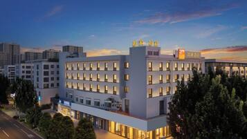 A multi-story hotel with a modern design, featuring a prominent entrance and a rooftop terrace.
