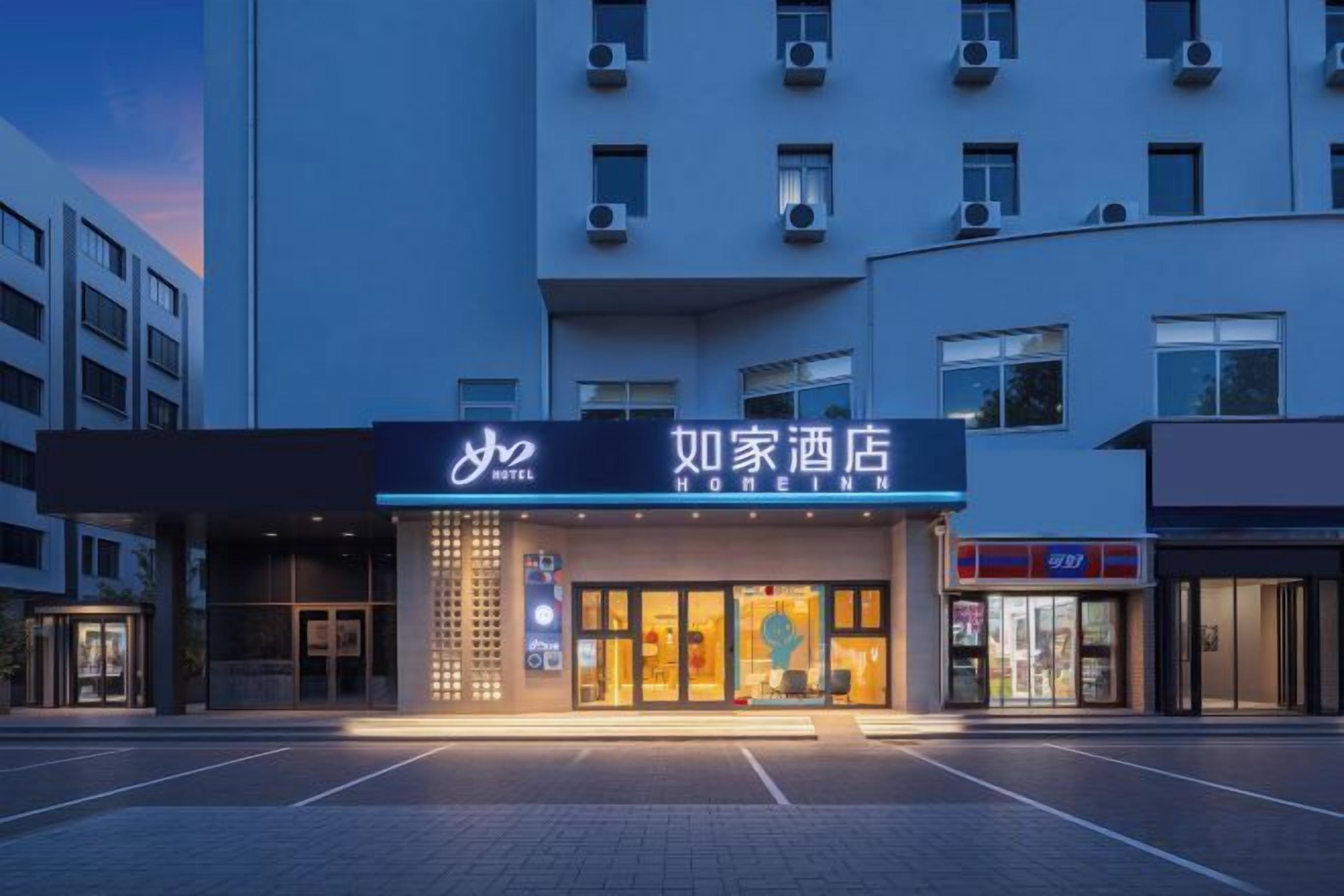 A hotel with a prominent sign, a parking lot, and a modern building facade.