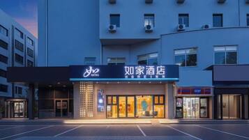 A hotel with a prominent sign, a parking lot, and a modern building facade.