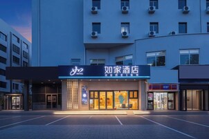 Un hotel con un letrero llamativo, un estacionamiento y una fachada de edificio moderna.