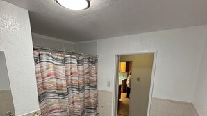 A bathroom with a shower curtain, toilet, and tiled walls.
