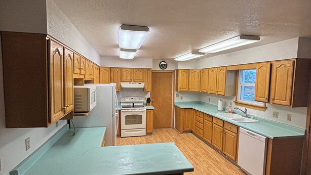 A kitchen with wooden cabinets, a central island, a microwave, an oven, and a dishwasher.