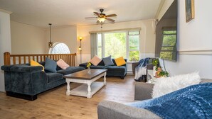A living room with two dark sofas, a white coffee table, and a ceiling fan. - Upscale Mountain Cottage with Hot Tub & Fireplace (Long Pond)