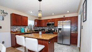 A modern kitchen with wooden cabinets, stainless steel appliances, and a granite countertop. - Upscale Mountain Cottage with Hot Tub & Fireplace (Long Pond)