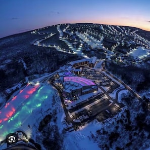 Vista aérea de un resort con un edificio grande, un paisaje nevado y un camino sinuoso.