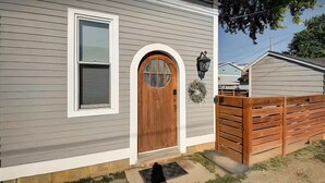 A house with a wooden front door, a window with shutters, and a small porch area. - HotTub~Gym~Fire Pit~5 Min to Mass Ave~Spacious for Groups~Indianapolis (Indianapolis)