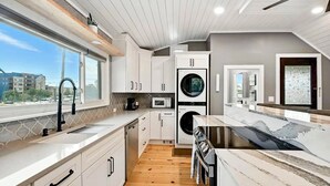 A modern kitchen with white cabinetry, a built-in oven, and a large window providing a view of the outside. - HotTub~Gym~Fire Pit~5 Min to Mass Ave~Spacious for Groups~Indianapolis (Indianapolis)