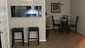 A modern kitchen with a built-in island, a dining area with a chandelier, and a white ceiling with a vent.