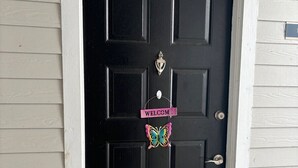 A black door with a 'WELCOME' sign and a butterfly decoration.