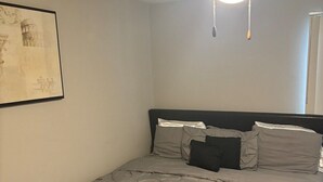 A bedroom with a bed, a ceiling fan, and a framed picture on the wall.