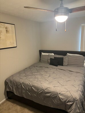 Un dormitorio con cama, ventilador de techo y un cuadro en la pared.