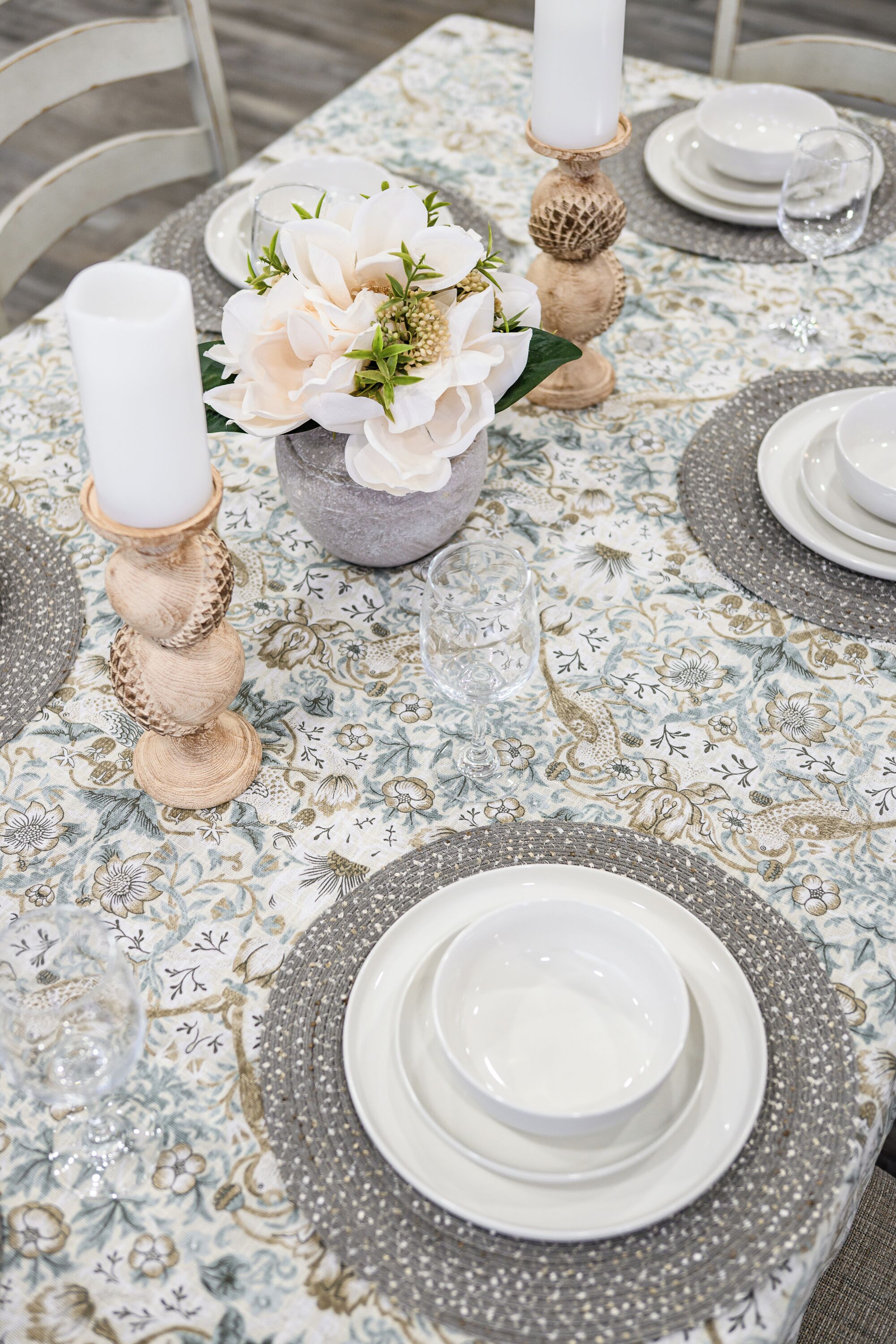 Une table dressée avec de l’argenterie, des assiettes blanches et un centre de table composé de fleurs blanches.