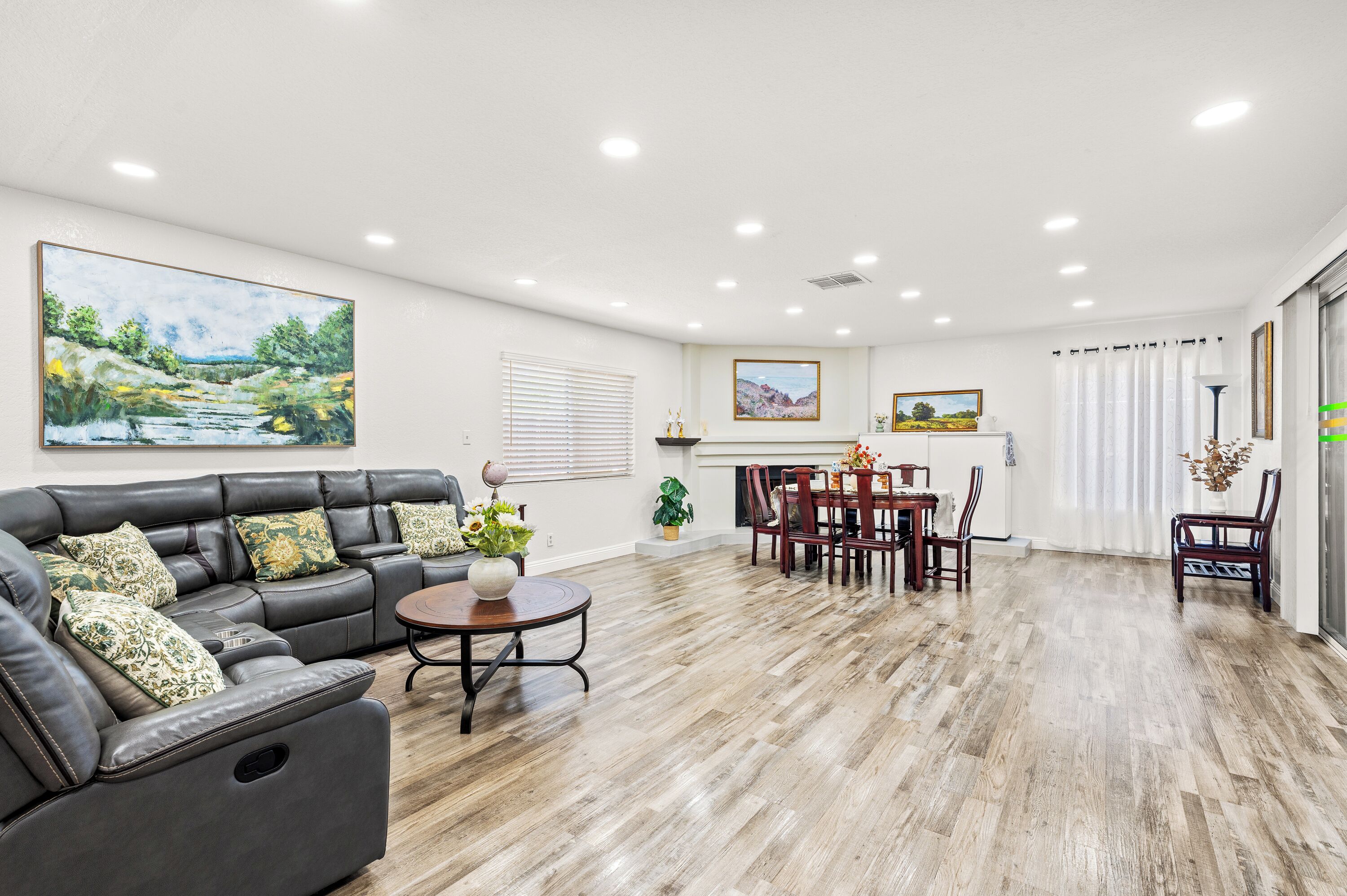 A spacious living room with a leather sofa, dining table, and chairs.