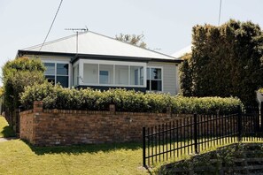 Una casa de un piso con un muro de ladrillo y una valla de metal negro.