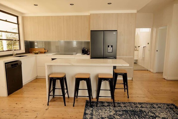 Une cuisine moderne dotée d’un grand îlot central, de tabourets de bar et d’un réfrigérateur encastré.