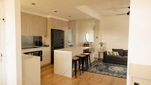 A modern kitchen with a marble island, wooden cabinets, and a built-in oven. - Pet Friendly 3 Bed Home w Workspace & Creek Views (Tighes Hill)