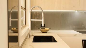 A modern kitchen with a marble countertop, a sink with a vessel sink, and wooden cabinetry.